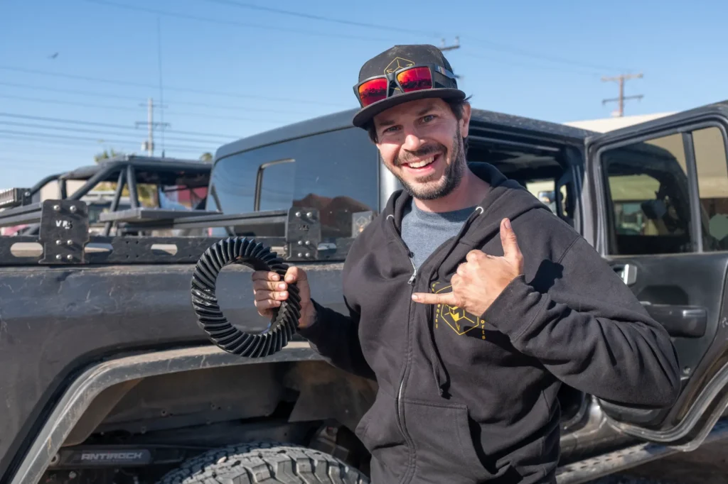 A man holding an object in front of a truck.