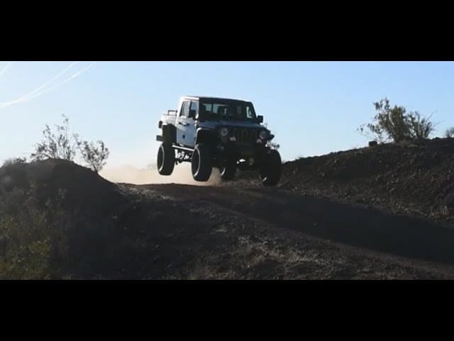 A white jeep driving down the side of a hill.